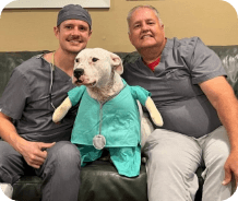 Two smiling dental team members with dog