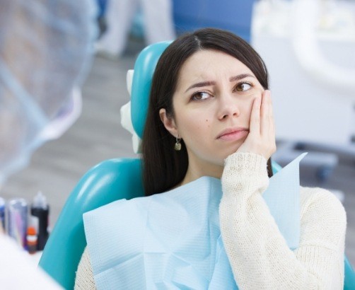 Woman holding cheek before emergency dentistry