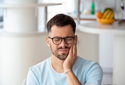 Man with black glasses experiencing toothache