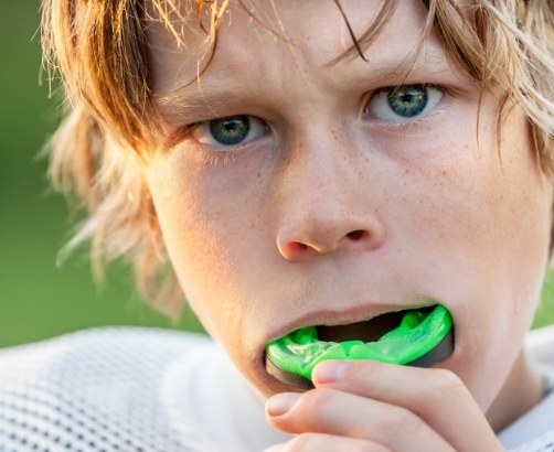 Child placing green athletic mouthguard