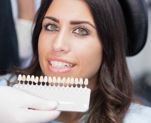 Woman's smile compared with veneers shade options during cosmetic dentistry treatment