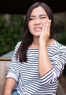 a woman holding her cheek due to injury