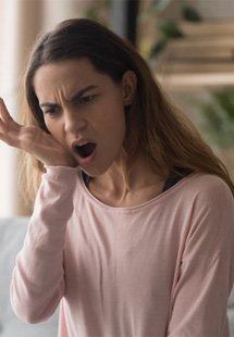 a woman touching her jaw due to pain