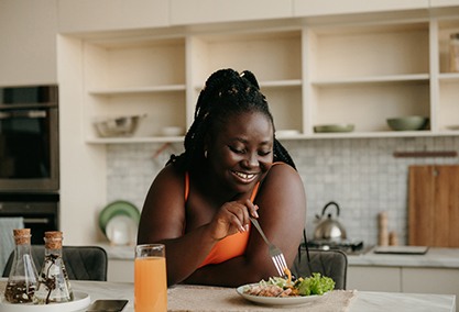 Woman smiling while eating healthy snack at home