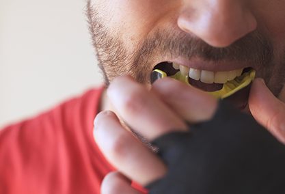 Man putting on yellow and black mouthguard