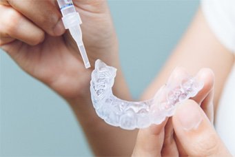 a person placing whitening gel into trays