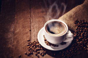 Cup of coffee on plate surrounded by beans