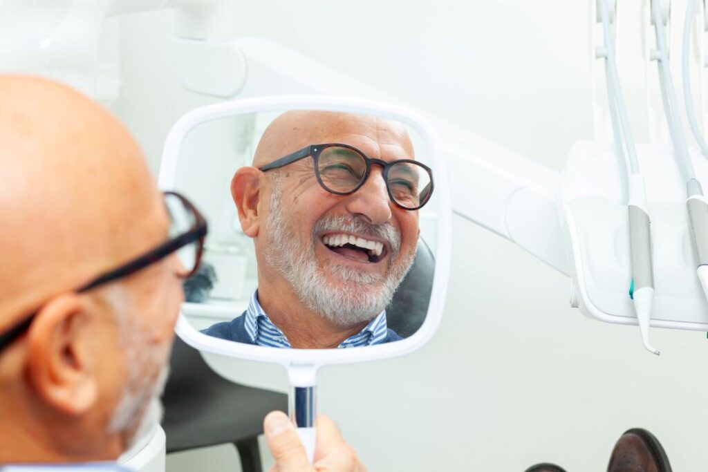 A man smiling in the mirror at his new dental implants