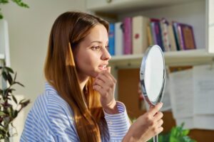 Woman looking at a bump on her gums
